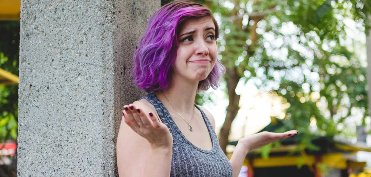 woman with purple hair shrugging