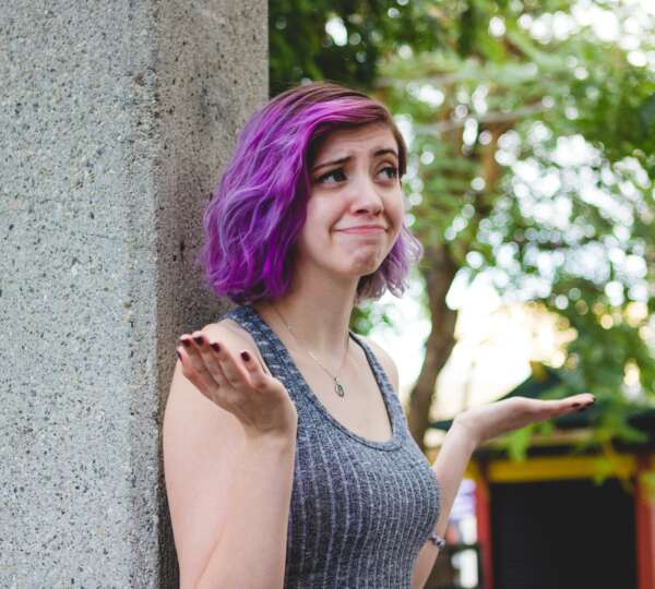 woman with purple hair shrugging